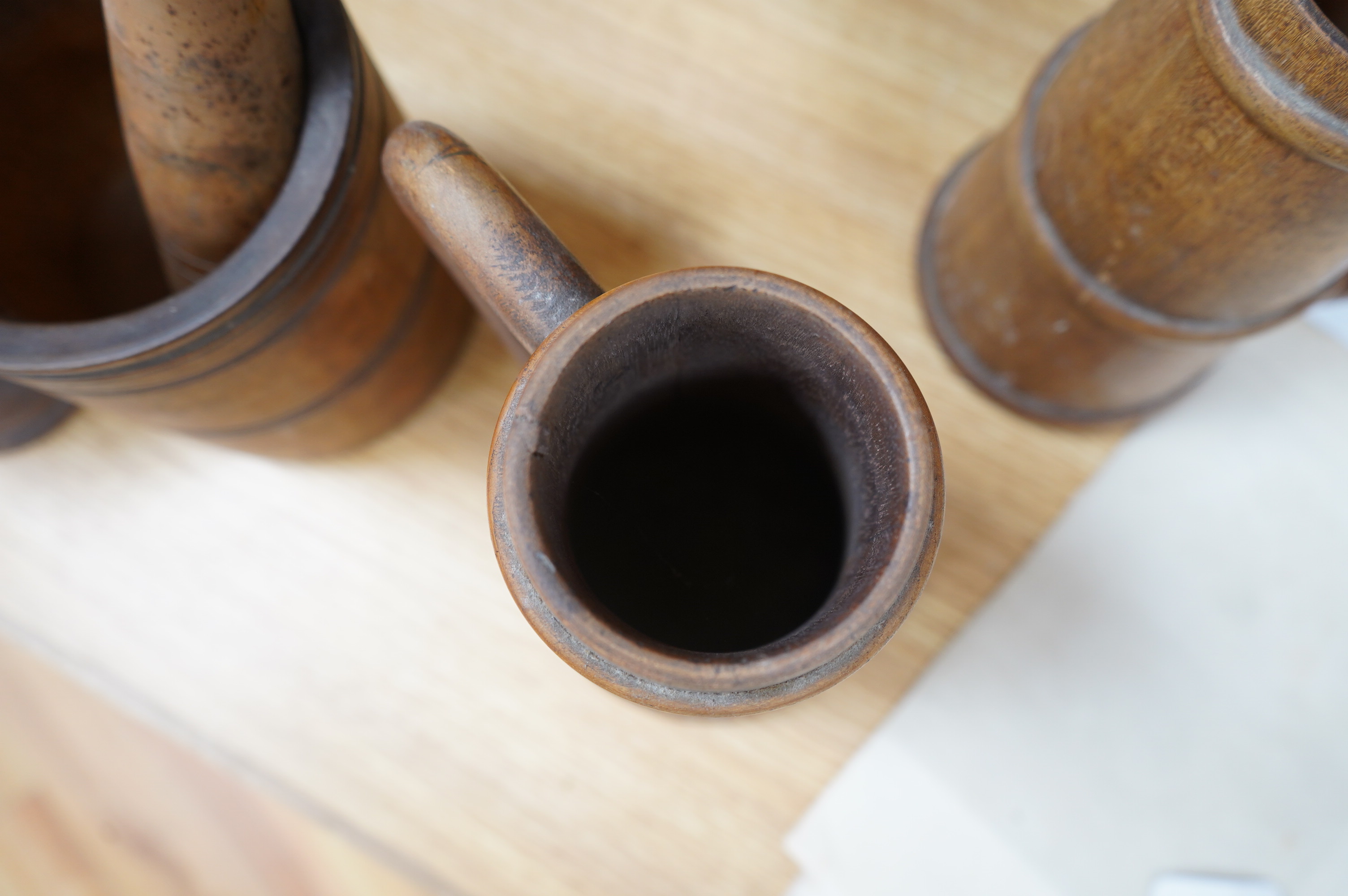 A pair of staved beech flagons, 23cm high, a wooden pestle and mortar, 17.5cm, and turned wood lidded bowl, 18cm (5). Condition - fair